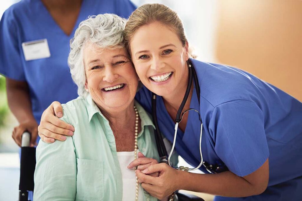 Older adults sitting together in a sunny communal room engaging in a group discussion with supportive staff nearby.