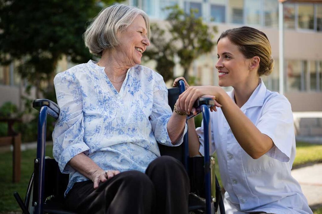 Adult family members review a resident’s care paperwork with an assisted living nurse at a dining table.